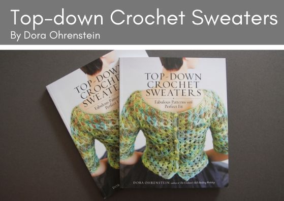 Two copies fo Top-down Crochet Sweaters by Dora Ohrenstein lie on greay background.  The front cover shows the back of a short haired woman with a lacey crocheted top in variegated green yarn.  It has green buttons fastening the back of the cardigan.