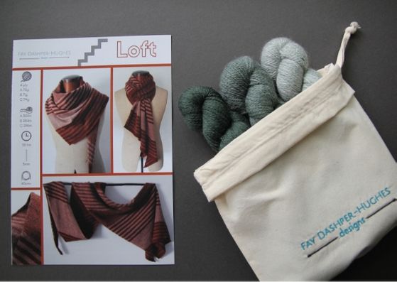 Knit kit for Loft shawl: on left is a hardcopy of the pattern showing the shawl off in three shades of copper and on the right are the three shades of green available getting darker from right to left, all sat in a rolled back bag with "Fay Dashper-Hughes Designs" embroidered on it.
