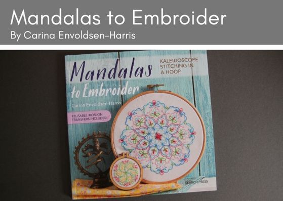 Mandalas to Embroider by Carine Envoldsen-Harris lies ona grey background.  The frony cover shows two mandalas leaning up against a turquoise wooden panel. The small mandala is in an embroidery hoop and features a furled circle design in greens, pink and yellow.  The large mandala is also in an embroidery hoop and shows a floral circular arrangement in blues, pinks and green.