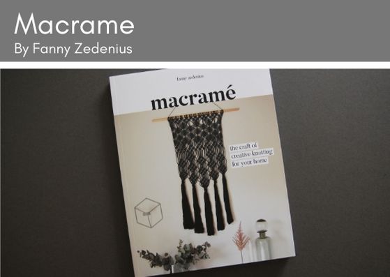 Macrame book by Fanny Zedenius lies on a grey background.  The frony cived shows a black macrame wall hanging against a cream wall with plants and a bottle featured beneath.  the macrame hangs off a wooden dowl rod.