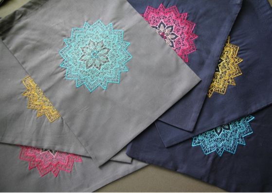 Embroidered mandala project bags: three grey ones on the left and three navy bags on the right.  Each bag has an embroidered manadala on it and the colours are either pink, yello or turquoise.