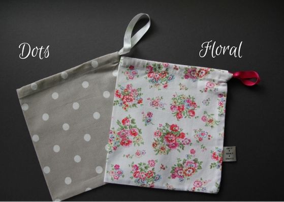 Two project bags lying on top of each other.  They are size small, beige colour with white dots on the left and a cream colour with a pink and green floral pattern on the right.