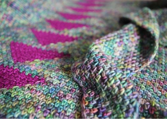 Arria crocheted shawl: close up f the shawl showing the spine of traingles in the bright pink against the variegated main colour - all crocheted in linen stitch.