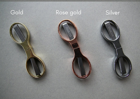 Grey background with three sets of foldaway scissors, all fully closed up.  L-R: gold, rose gols and silver.